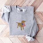 Sport Grey crewneck sweatshirt laid flat on a wood floor, embroidered in the center with a golden yellow lab carrying an American flag