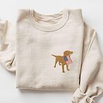 Sand crewneck sweatshirt laid flat with the smaller left chest placement of a golden lab carrying an American flag