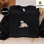 Black crewneck sweatshirt with a brown felt hat and dried bunny tail grass, embroidered with a smiling yellow Labrador lying down with its front paws stretched out