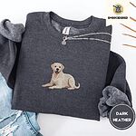 Dark Heather crewneck sweatshirt folded with ripped jeans and a silver chain necklace, embroidered with a smiling yellow Labrador lying down with its front paws stretched out