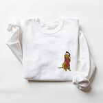 White crewneck sweatshirt laid flat with folded sleeves, embroidered with a small yellow Labrador in a red Santa hat and a long fringed red scarf on the left chest