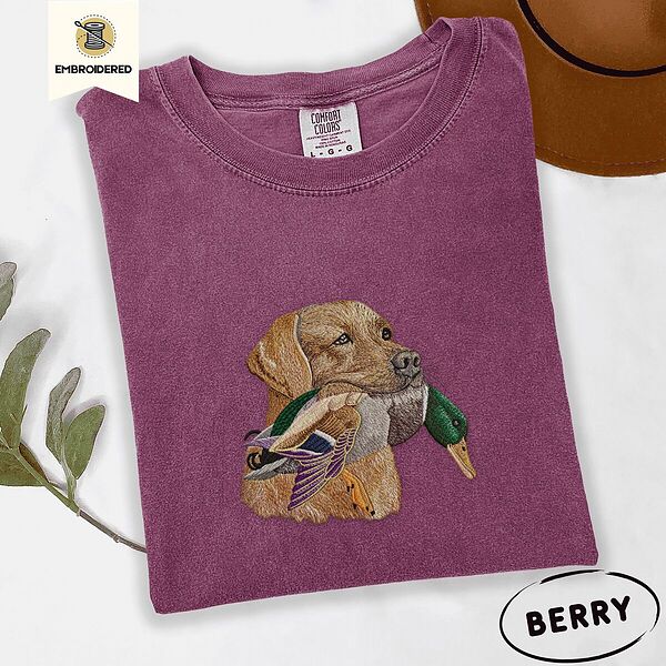 Berry Comfort Colors T-shirt embroidered with a yellow Labrador head carrying a mallard drake in its mouth