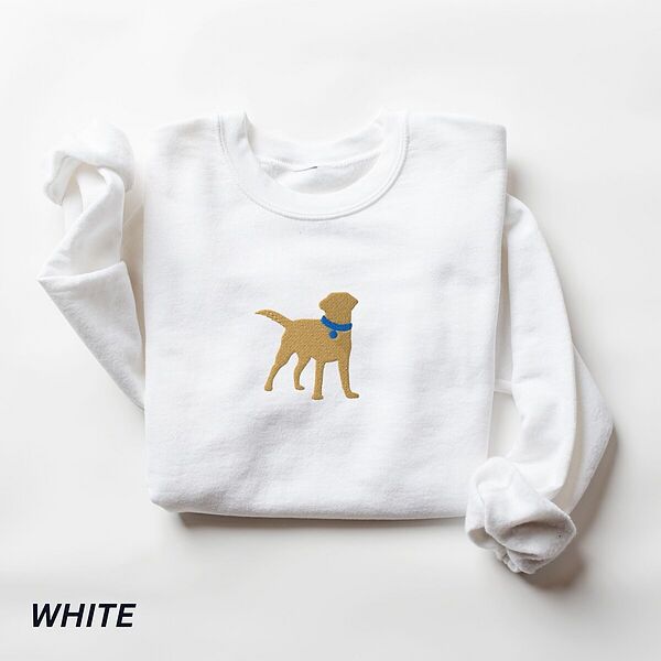 White crewneck sweatshirt laid flat on white, embroidered with a golden yellow Labrador silhouette standing in a blue collar and round tag in the center of the chest