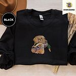 Black crewneck sweatshirt with a brown felt hat and dried bunny tail grass, embroidered with a yellow Labrador head carrying a mallard drake in its mouth