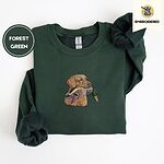 Forest Green crewneck sweatshirt folded on a white background, embroidered with a yellow Labrador head carrying a mallard drake in its mouth