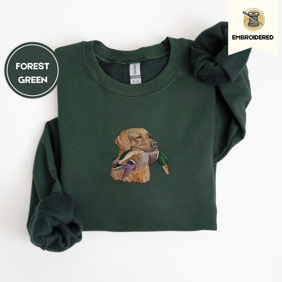 Yellow Lab Sweatshirt – Forest Green Forest Green crewneck sweatshirt folded on a white background, embroidered with a yellow Labrador head carrying a mallard drake in its mouth