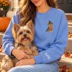 Yorkie mom wearing the Heather Deep Royal Halloween sweatshirt with her Yorkshire Terrier on a fall porch